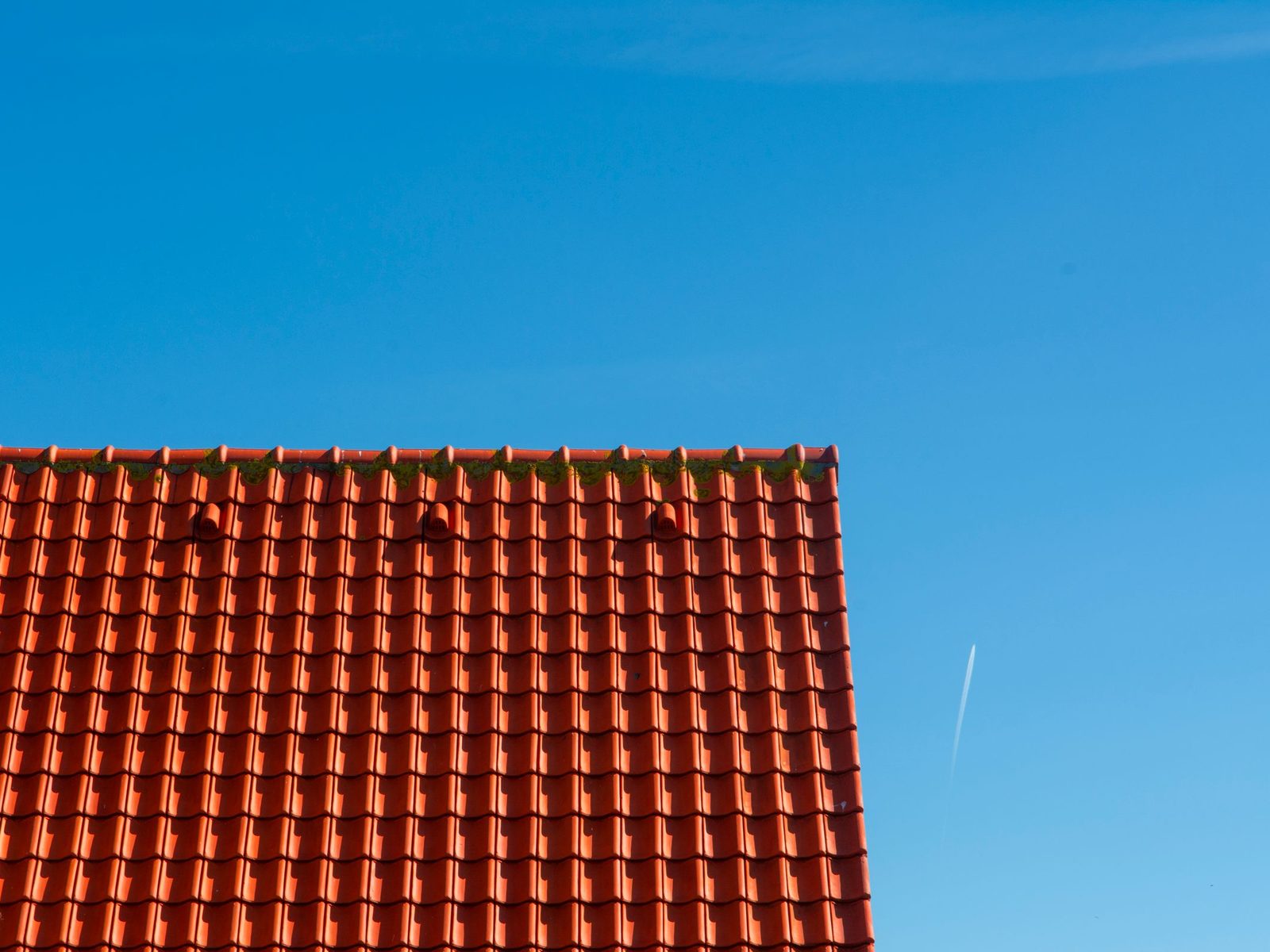Red tile roof edge against a clear blue sky